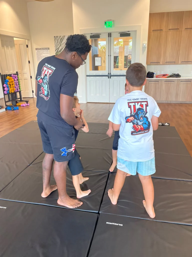 Instructor guiding children during martial arts training